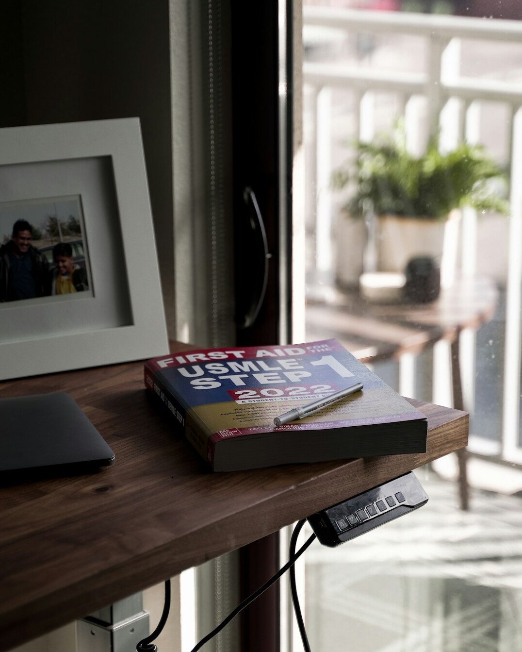 Woman writing notes at a bright desk with a laptop